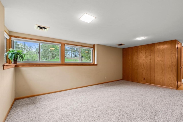 spare room featuring light colored carpet, plenty of natural light, visible vents, and baseboards