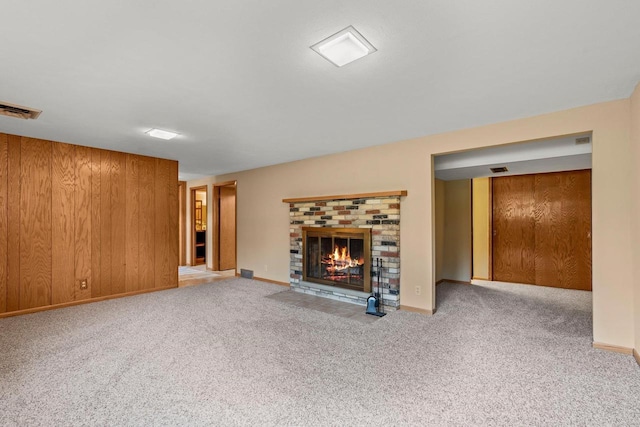 unfurnished living room with carpet flooring, visible vents, a fireplace, and baseboards