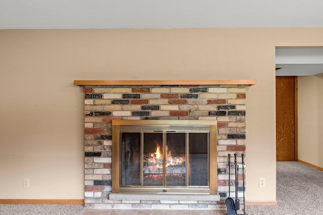 interior details featuring baseboards, a brick fireplace, and carpet