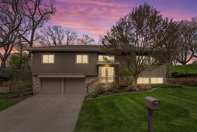 split foyer home featuring a yard, brick siding, an attached garage, and concrete driveway