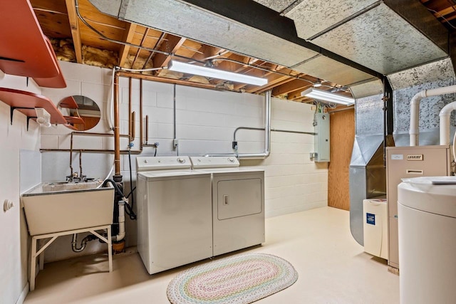 clothes washing area featuring washing machine and dryer, laundry area, a sink, and concrete block wall