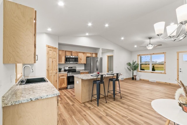 kitchen featuring a breakfast bar, a sink, light wood-style floors, stainless steel appliances, and a kitchen island