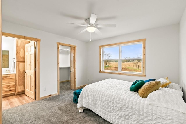 bedroom featuring ceiling fan, light colored carpet, a walk in closet, baseboards, and a closet