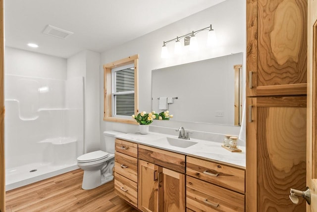bathroom featuring visible vents, walk in shower, wood finished floors, vanity, and toilet