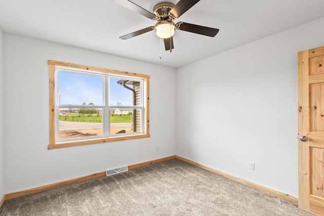 carpeted spare room featuring baseboards, a ceiling fan, and visible vents