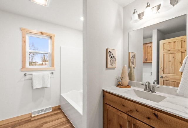 bathroom featuring visible vents, baseboards, wood finished floors, and vanity
