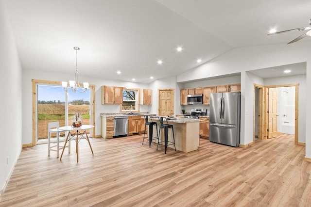 kitchen with a breakfast bar area, light wood-type flooring, a sink, a chandelier, and stainless steel appliances
