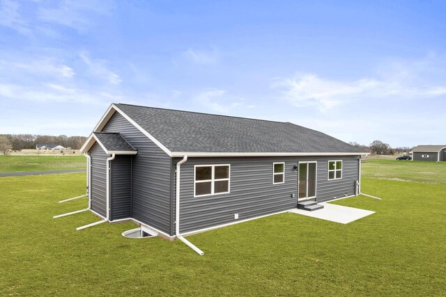 rear view of property with a lawn, a shingled roof, and entry steps