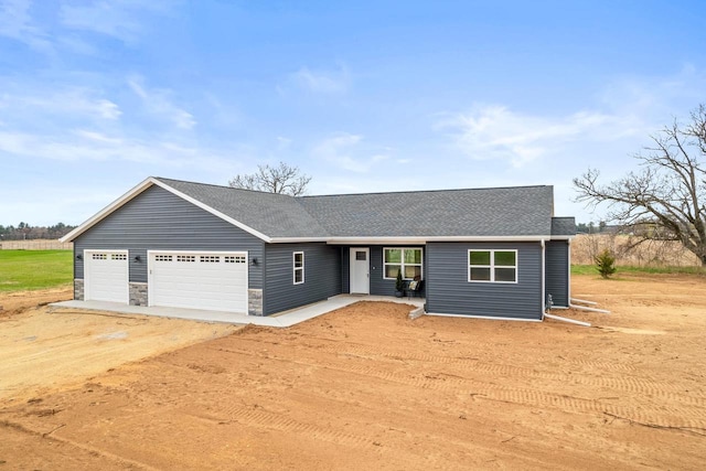 single story home featuring a garage, driveway, stone siding, and a shingled roof