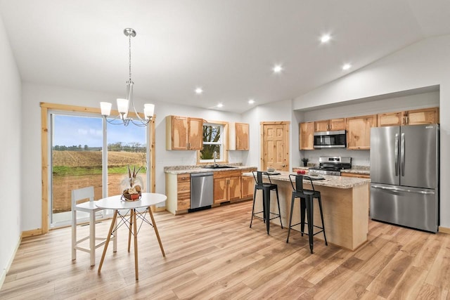 kitchen with a notable chandelier, appliances with stainless steel finishes, a sink, a kitchen island, and vaulted ceiling