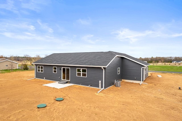 back of house with central AC unit, a shingled roof, and entry steps