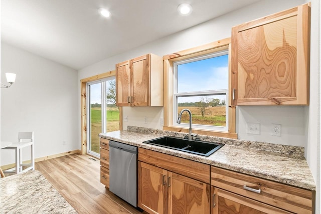 kitchen with stainless steel dishwasher, a sink, baseboards, light countertops, and light wood-style floors