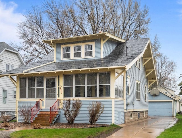 view of front of home with roof with shingles, an outdoor structure, a sunroom, and a garage