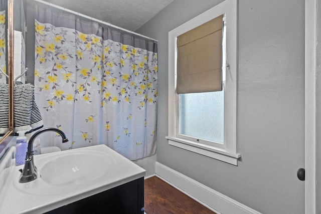 bathroom with baseboards, curtained shower, vanity, and wood finished floors