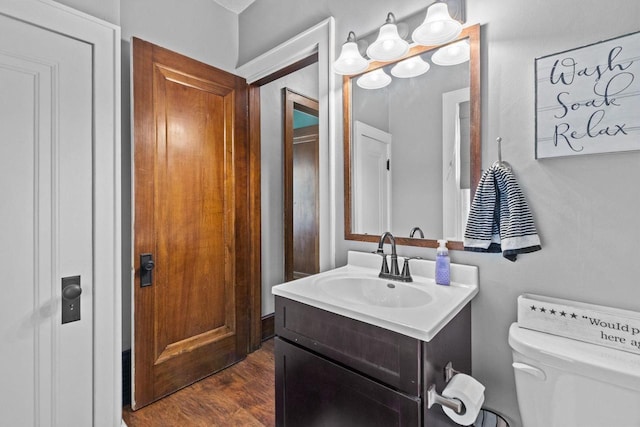 half bath with vanity, wood finished floors, and toilet