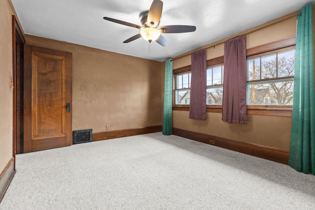 carpeted empty room featuring ceiling fan, visible vents, and baseboards
