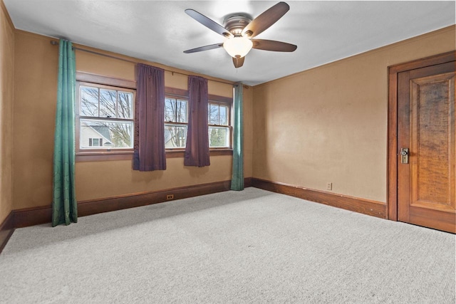 carpeted empty room with baseboards, ceiling fan, and a wealth of natural light