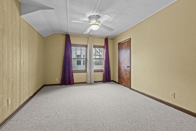 carpeted spare room with ceiling fan, vaulted ceiling, and baseboards