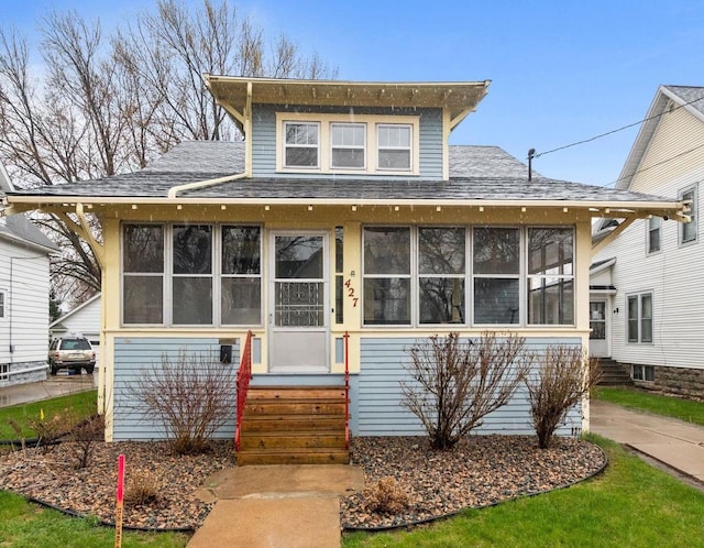 view of front of home with a sunroom, roof with shingles, and entry steps