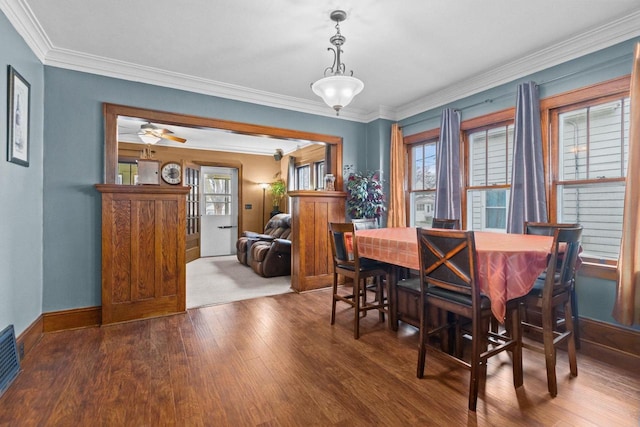 dining room featuring crown molding, baseboards, visible vents, and wood finished floors