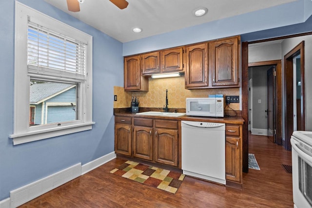 kitchen with backsplash, visible vents, dark wood finished floors, a sink, and white appliances