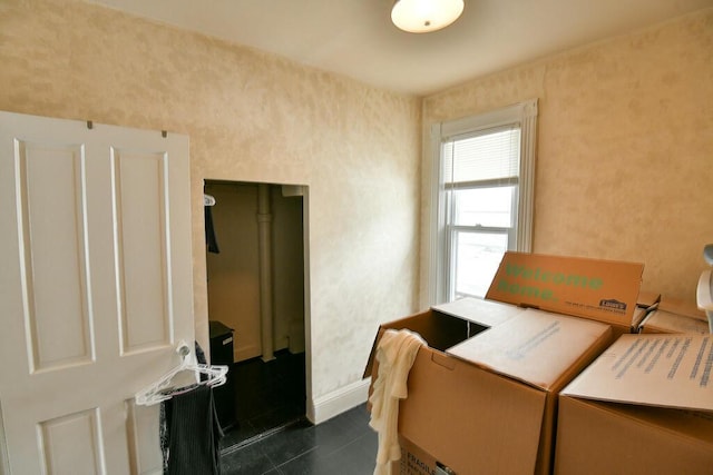 bedroom with separate washer and dryer, baseboards, and dark tile patterned flooring