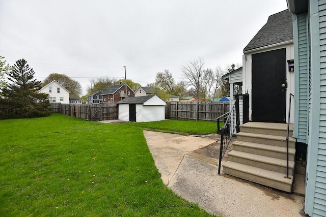 view of yard with a residential view, an outdoor structure, a fenced backyard, a shed, and entry steps