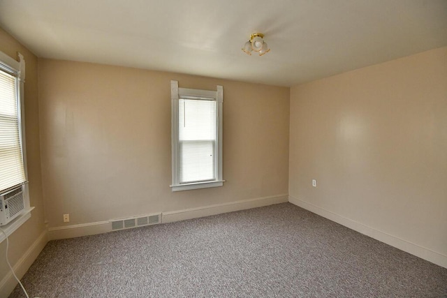 carpeted spare room with baseboards, a wealth of natural light, cooling unit, and visible vents