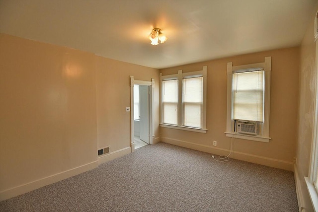 carpeted spare room featuring baseboards, visible vents, and cooling unit