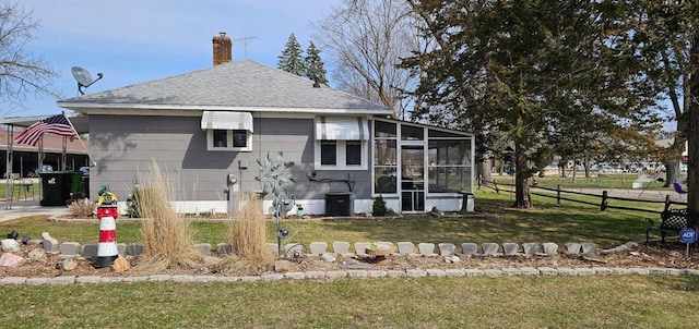 556 Gold St, Green Lake, WI 54941 - back of property with a sunroom, roof with shingles, a chimney, and central AC unit