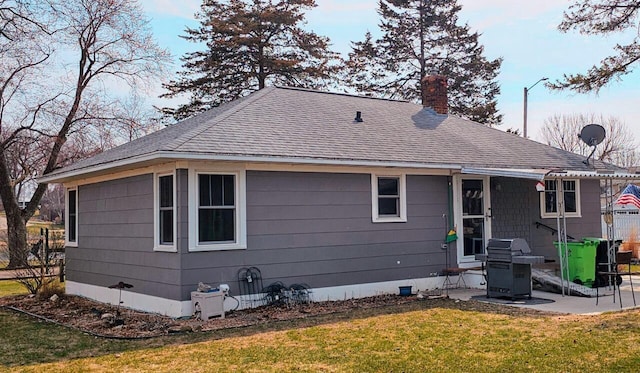 556 Gold St, Green Lake, WI 54941 - back of house with a chimney, a shingled roof, and a lawn