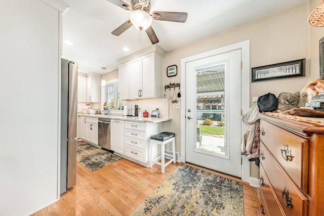 556 Gold St, Green Lake, WI 54941 - kitchen with appliances with stainless steel finishes, light wood-style flooring, white cabinetry, a ceiling fan, and hanging light fixtures