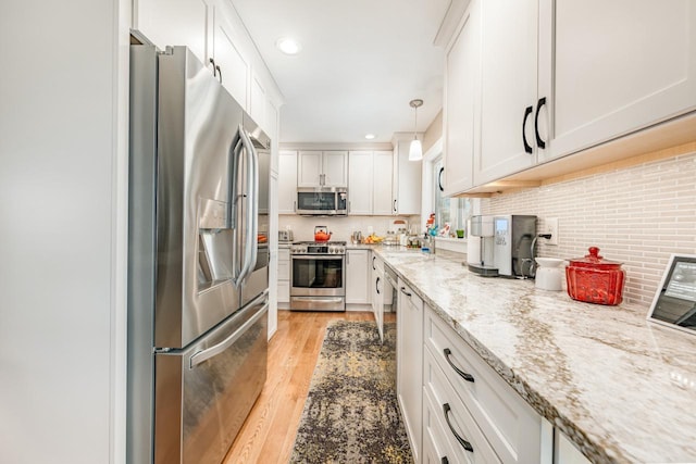 556 Gold St, Green Lake, WI 54941 - kitchen with stainless steel appliances, light wood finished floors, white cabinets, light stone countertops, and a sink