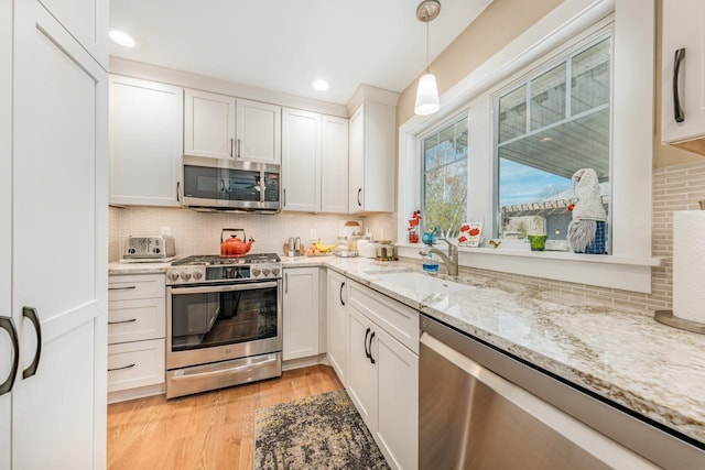 556 Gold St, Green Lake, WI 54941 - kitchen featuring appliances with stainless steel finishes, a sink, decorative backsplash, white cabinets, and light stone countertops