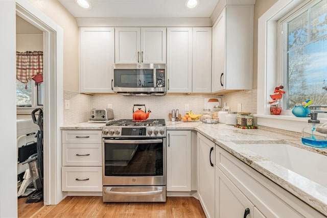 556 Gold St, Green Lake, WI 54941 - kitchen with appliances with stainless steel finishes, white cabinetry, decorative backsplash, and recessed lighting