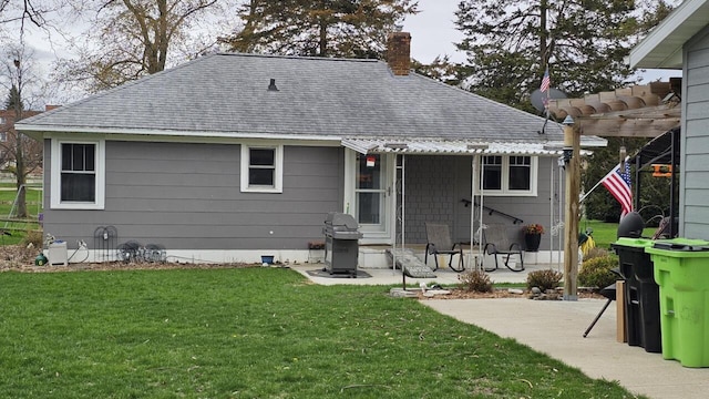 556 Gold St, Green Lake, WI 54941 - back of property with roof with shingles, a chimney, a pergola, and a lawn