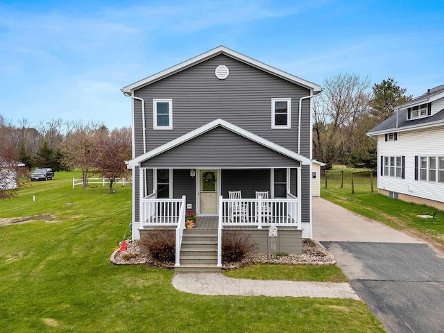 traditional-style home with a porch, aphalt driveway, and a front lawn