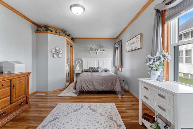 bedroom with multiple windows, crown molding, and wood finished floors