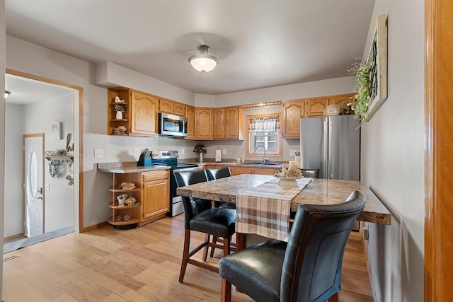 kitchen with light countertops, open shelves, appliances with stainless steel finishes, and a sink