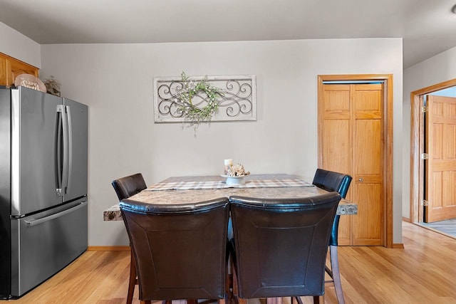 dining area with baseboards and light wood finished floors