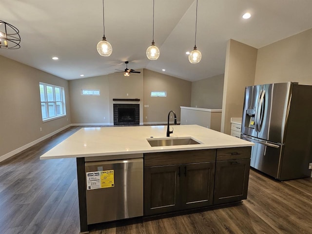 kitchen with a sink, a fireplace, stainless steel appliances, a ceiling fan, and dark wood-type flooring