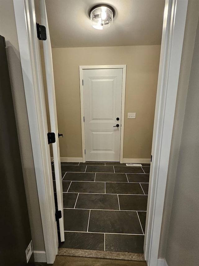 doorway to outside featuring baseboards and tile patterned floors