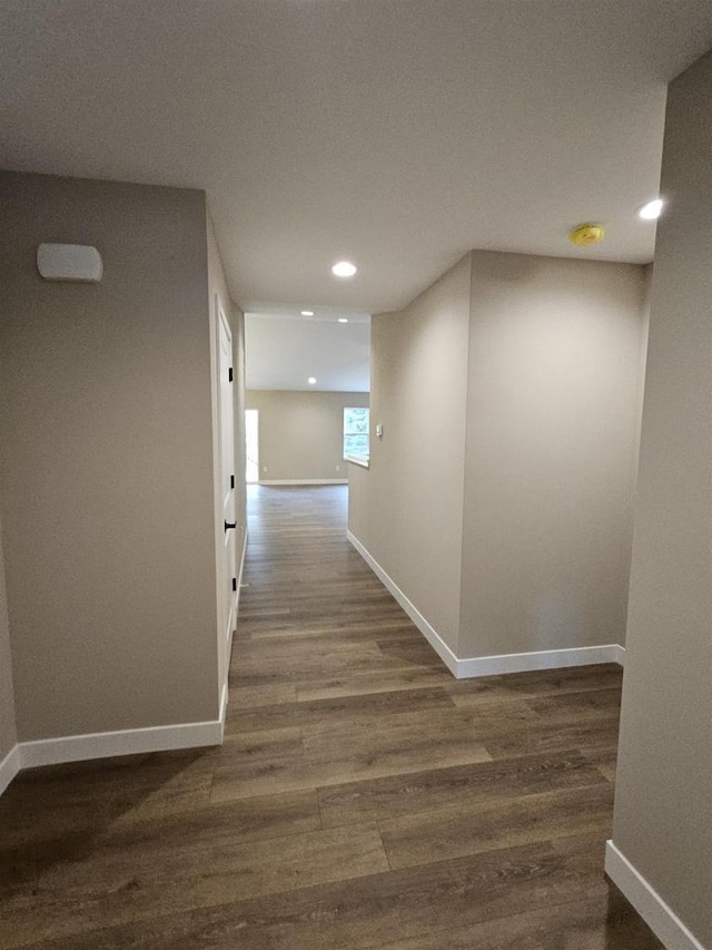 hallway featuring baseboards, recessed lighting, and wood finished floors