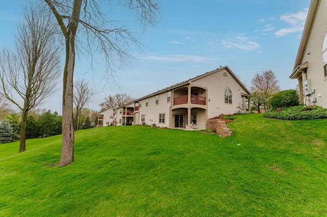 rear view of property featuring a yard and a balcony