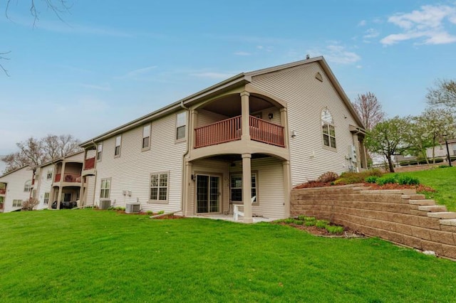 rear view of property featuring a lawn, central AC unit, and a balcony