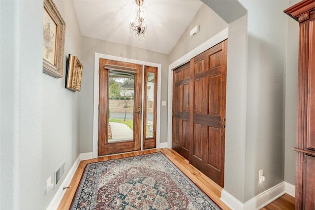 entryway with baseboards, a notable chandelier, wood finished floors, and visible vents