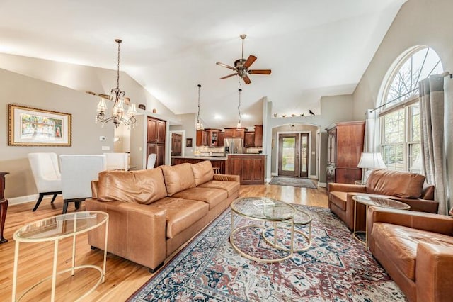 living room with baseboards, vaulted ceiling, light wood-style flooring, and ceiling fan with notable chandelier