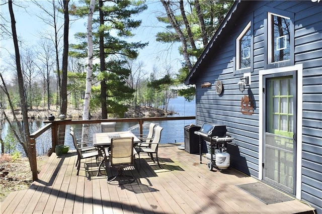 wooden terrace featuring a water view, outdoor dining space, and a grill