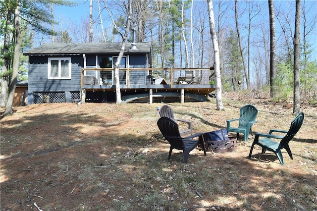 rear view of property featuring an outdoor fire pit and a wooden deck