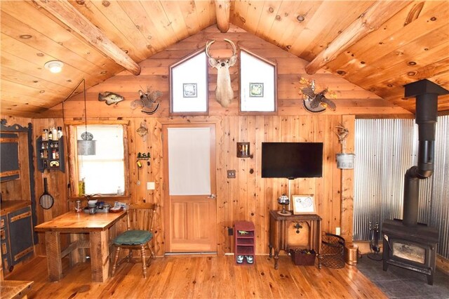 living area featuring plenty of natural light, a wood stove, lofted ceiling with beams, and hardwood / wood-style flooring